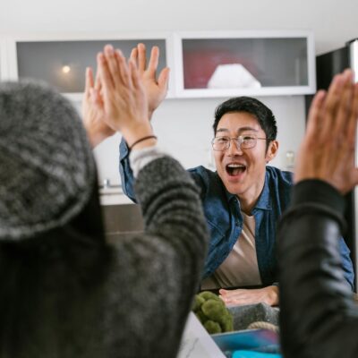 Photo by RDNE Stock project A diverse group of adults sharing a celebratory high five in a modern kitchen setting.