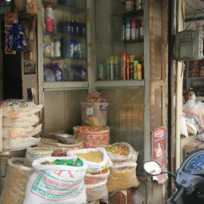 Image of a traditional Indian grocery storefront showcasing sacks of grains and products displayed outside.