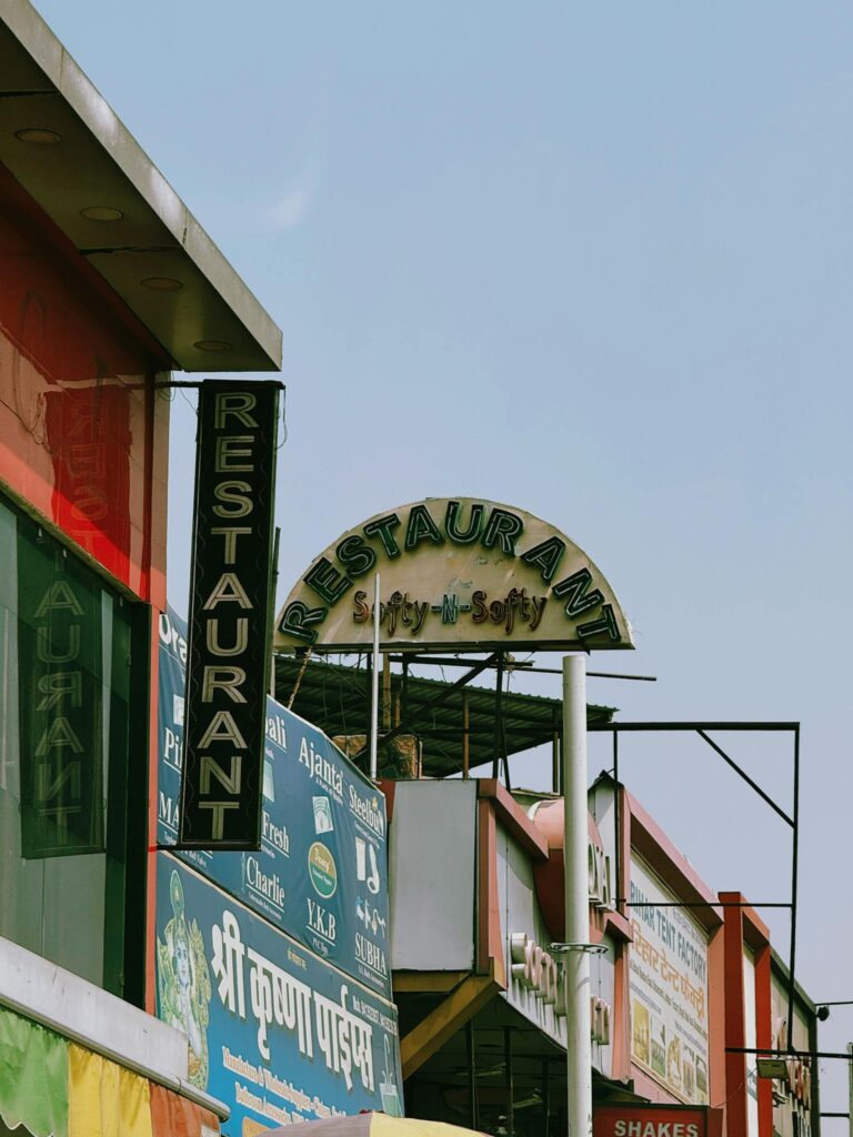 Vibrant market scene showcasing a variety of restaurant signs in India under a clear sky.